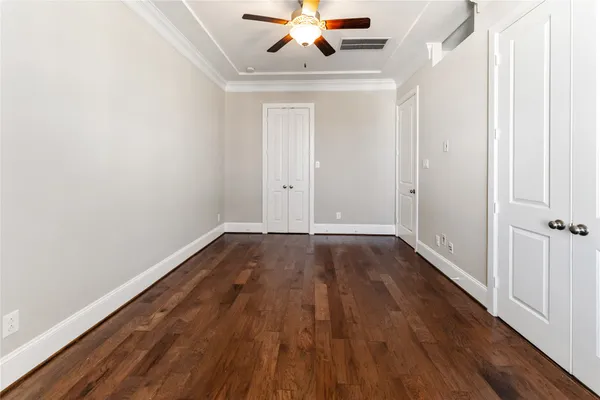 an empty room with wooden floor fan and windows