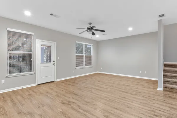a view of an empty room with a window and wooden floor