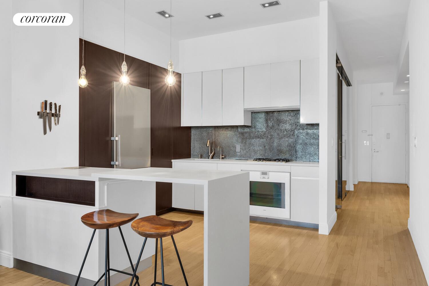 252 7th Avenue, Unit 16J Manhattan, NY 10001 - Photo 3 of 8 a living room with stainless steel appliances kitchen island granite countertop furniture and a fireplace