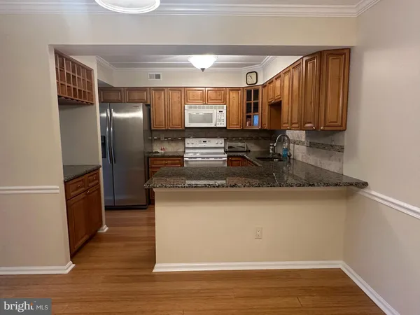 a kitchen with kitchen island granite countertop a refrigerator and a sink