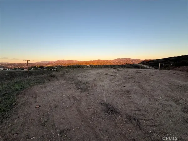 a view of a dry yard with wooden fence