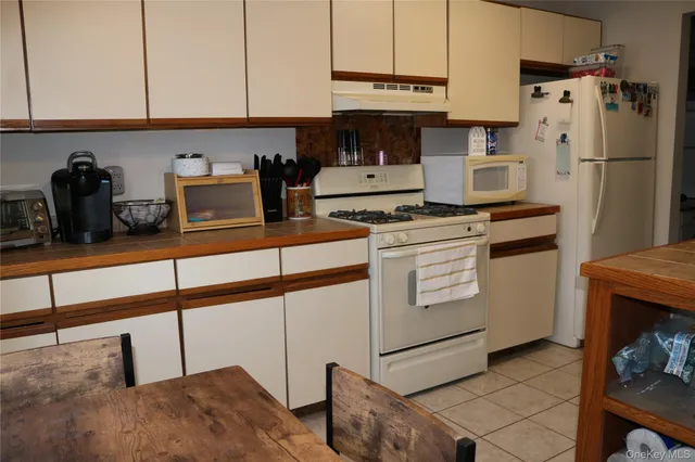 a kitchen with granite countertop white cabinets and white appliances