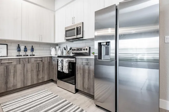 a kitchen with stainless steel appliances granite countertop a refrigerator a stove and a sink with wooden floor