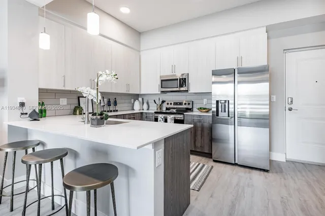 a kitchen with kitchen island a refrigerator a stove a sink and chairs