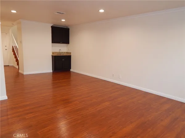 an empty room with wooden floor and a sink
