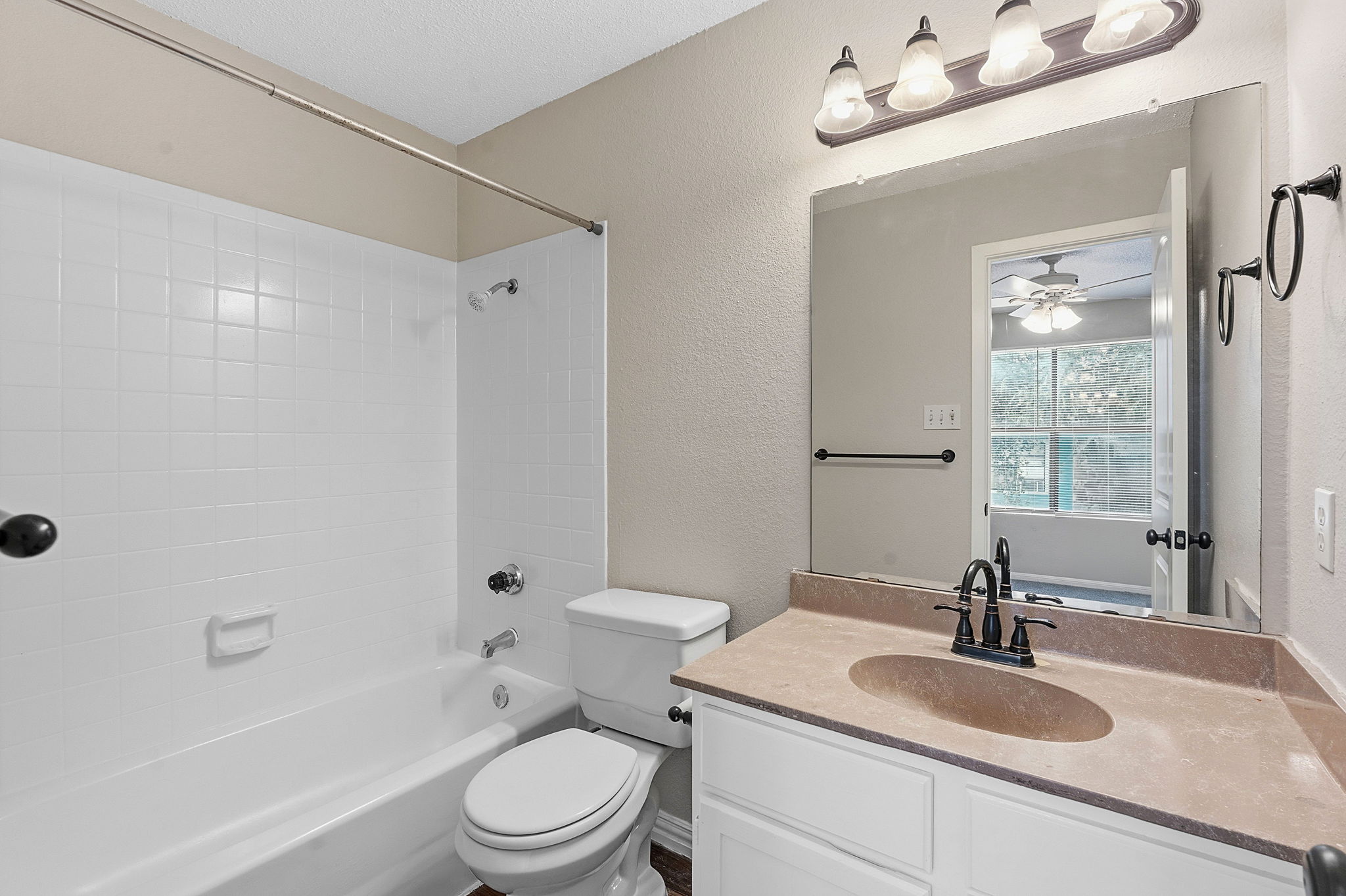 8811 Schick Road Austin, TX 78729 - Photo 19 of 27 A well-appointed bathroom offers a clean tub-shower combo and a vanity with a large mirror.