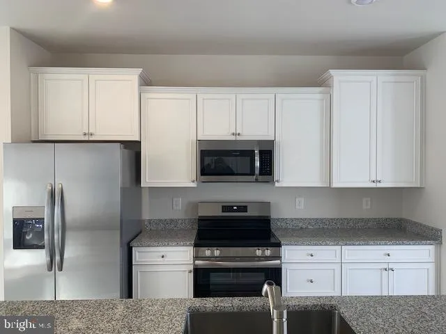 a kitchen with cabinets stainless steel appliances and a counter space