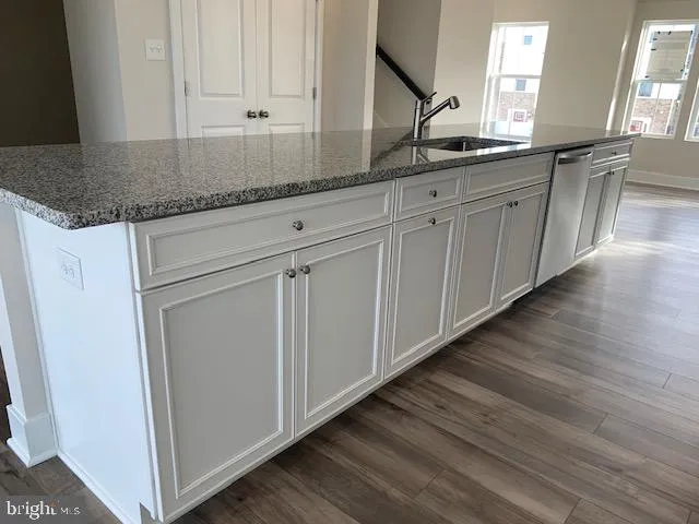 a kitchen with granite countertop white cabinets and sink