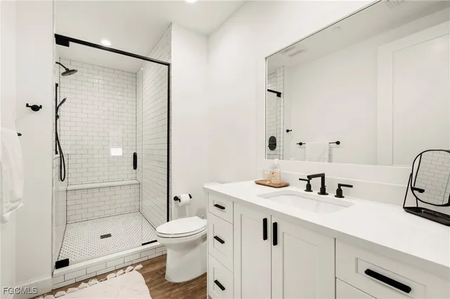 a bathroom with a shower sink vanity mirror and toilet