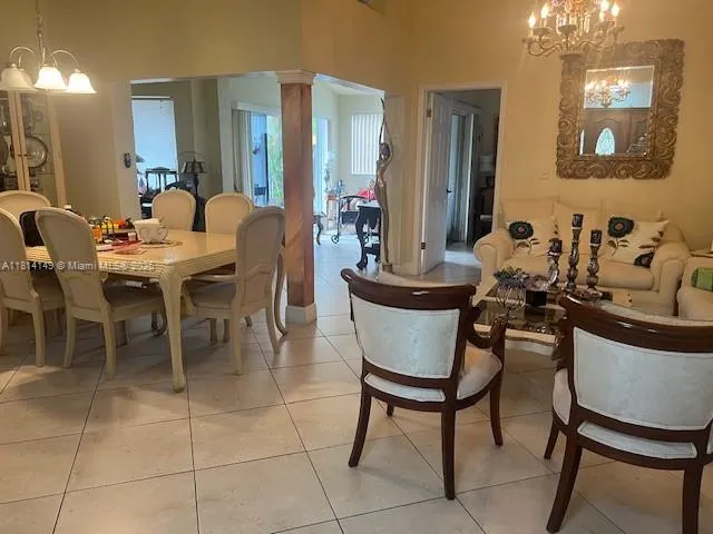 a living room with couches a mirror and a dining table with wooden floor