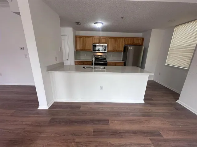 a view of kitchen with stainless steel appliances wooden floor