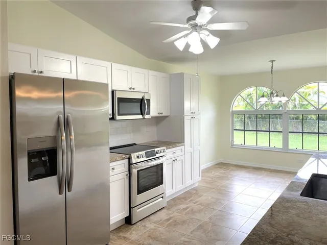 a kitchen with stainless steel appliances granite countertop a refrigerator a stove a microwave oven with cabinets and wooden floor