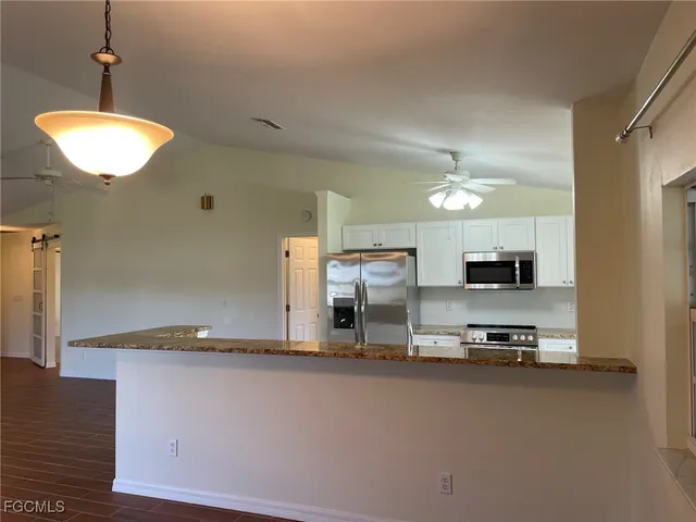 a kitchen with kitchen island granite countertop a sink a stove and a refrigerator