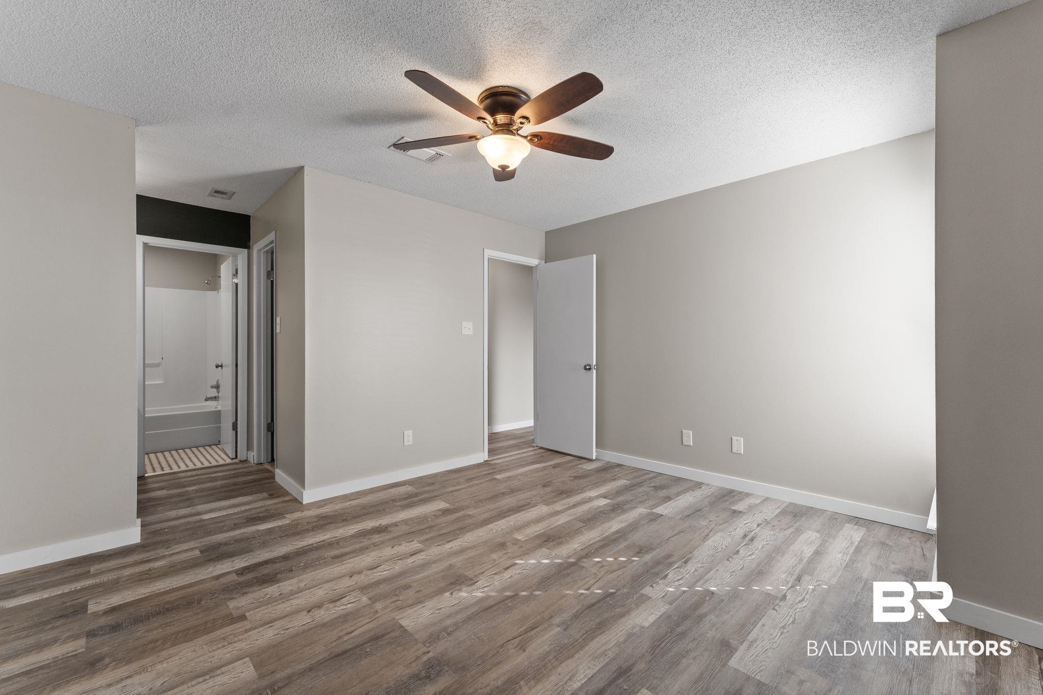 128 West Satsuma Avenue, Unit 128 Foley, AL 36535 - Photo 18 of 41 Unfurnished bedroom featuring a ceiling fan, a textured ceiling, light wood finished floors, and connected bathroom