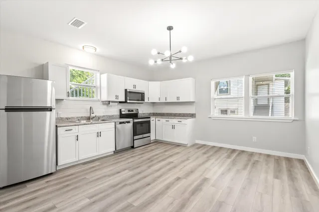 a kitchen with granite countertop white cabinets and refrigerator
