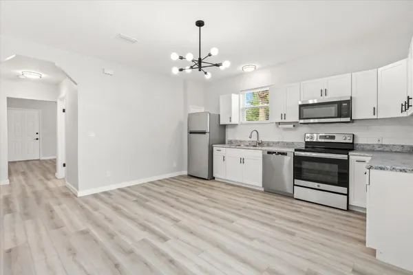 a kitchen with granite countertop a sink cabinets stainless steel appliances and a window