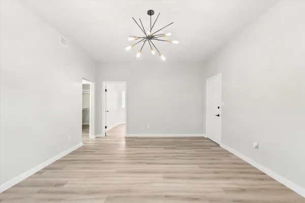 a view of an empty room with wooden floor and a ceiling fan