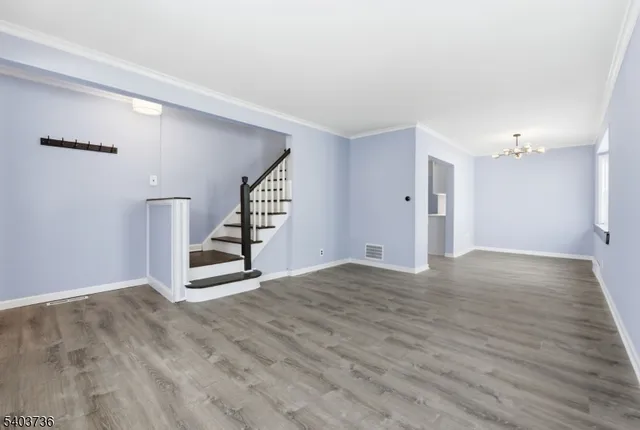 a view of an empty room with wooden floor and stairs