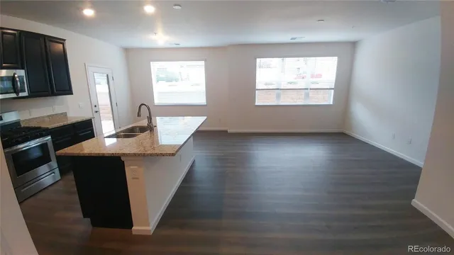 a kitchen with stainless steel appliances granite countertop a sink a microwave cabinets and wooden floor