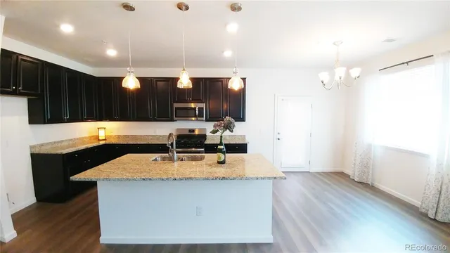 a kitchen with kitchen island granite countertop a sink cabinets and wooden floor