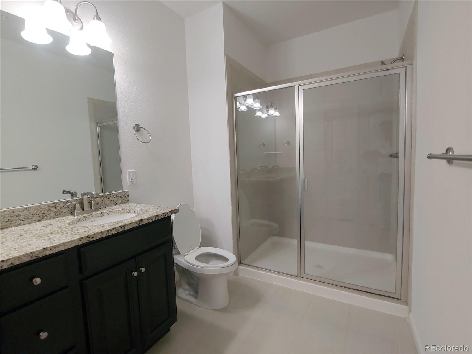 4569 Copeland Lane, Unit 101 Highlands Ranch, CO 80126 - Photo 8 of 17 a bathroom with a granite countertop sink a toilet and shower