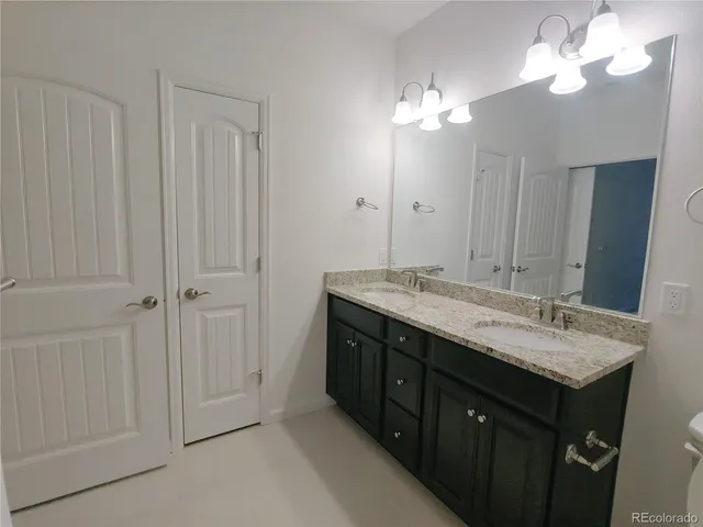 a bathroom with a granite countertop sink a light fixture and a mirror