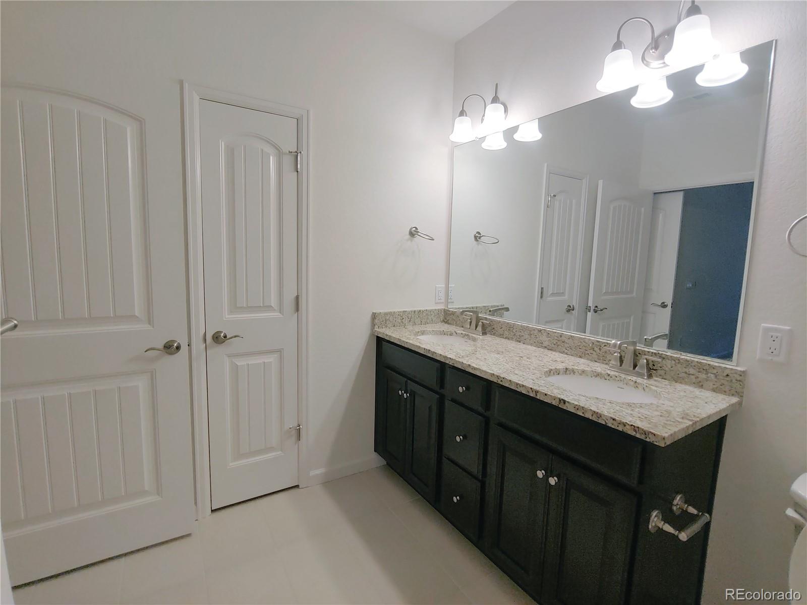 4569 Copeland Lane, Unit 101 Highlands Ranch, CO 80126 - Photo 9 of 17 a bathroom with a granite countertop sink a light fixture and a mirror