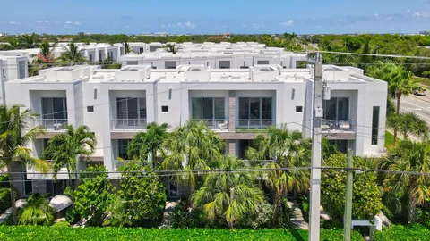 front view of a brick house with a large window and potted plants