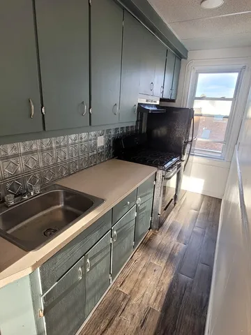 a kitchen with wooden cabinets a sink and a stove with wooden floor