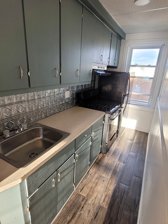 303 Cambridge Street, Unit 3 Fall River, MA 02721 - Photo 8 of 9 a kitchen with wooden cabinets a sink and a stove with wooden floor