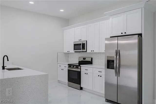 a kitchen with white cabinets appliances and a sink