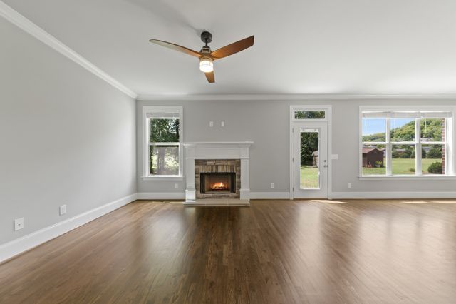 a view of an empty room with wooden floor fireplace and a window
