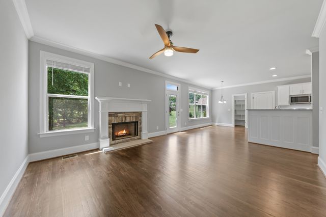 a view of an empty room with wooden floor fireplace and a window