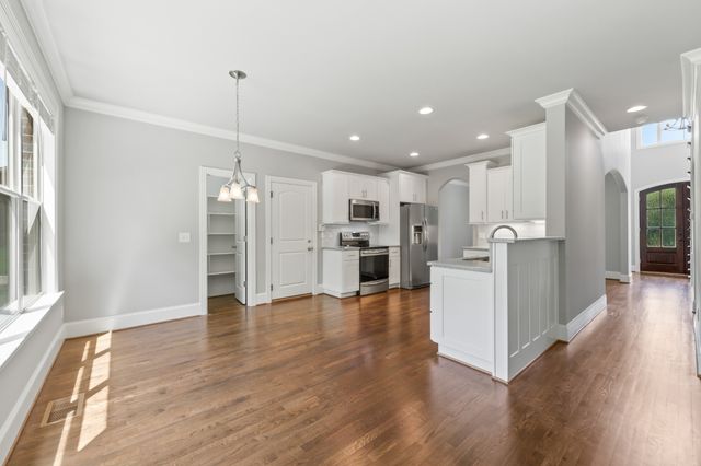 a view of kitchen with stainless steel appliances refrigerator wooden floor and window
