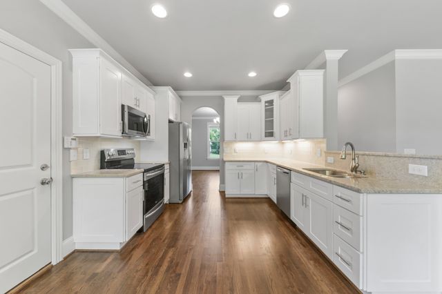 a kitchen with granite countertop white cabinets and stainless steel appliances