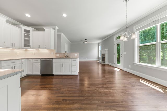 an empty room with wooden floor chandelier and windows