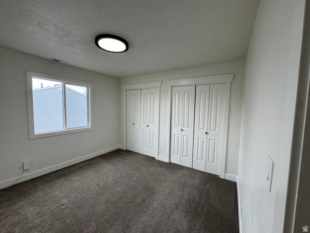 608 South 500 West, Unit 3 Provo, UT 84601 - Photo 25 of 35 Bedroom featuring neutral carpeting, a dual-pane window with white trim, two white bi-fold closet doors, and a flush-mount ceiling light fixture
