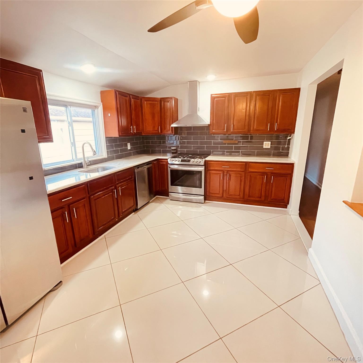 878 Rensselaer Avenue Staten Island, NY 10309 - Photo 2 of 35 Kitchen featuring stainless steel appliances, wall chimney exhaust hood, decorative backsplash, ceiling fan, and light stone countertops