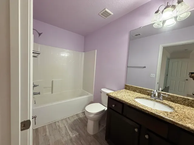 a bathroom with a granite countertop sink a toilet a mirror and shower