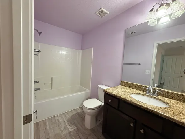 a bathroom with a granite countertop sink a toilet a mirror and shower