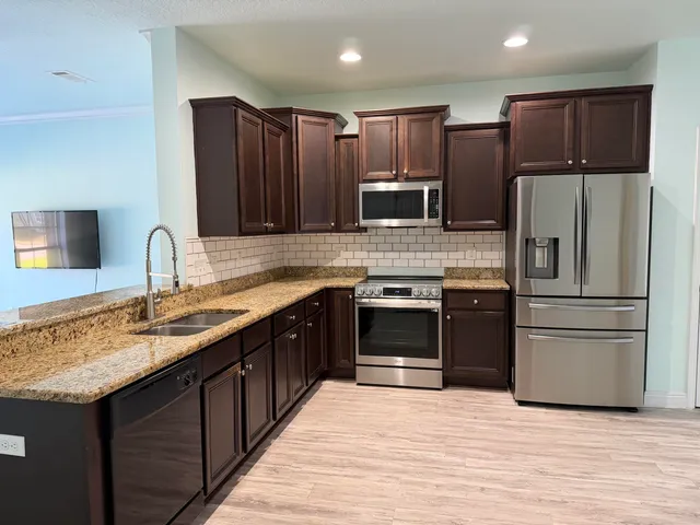 a kitchen with kitchen island granite countertop stainless steel appliances and wooden cabinets