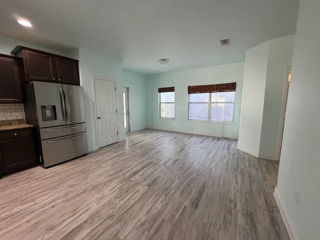 a view of a kitchen with wooden floor electronic appliances and window