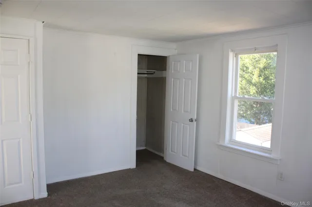 a view of an empty room with closet and a window