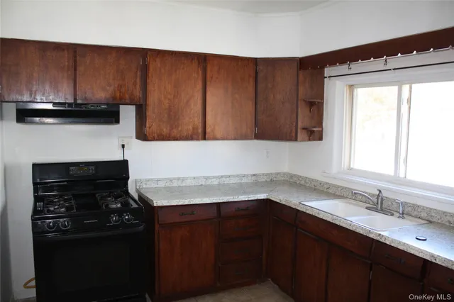 a kitchen with granite countertop wooden cabinets and a stove top oven