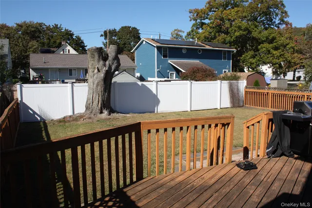 a view of a deck with wooden floor and barbeque grill with a small yard