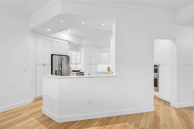 a view of kitchen with stainless steel appliances granite countertop a refrigerator a sink dishwasher and a stove with wooden floor