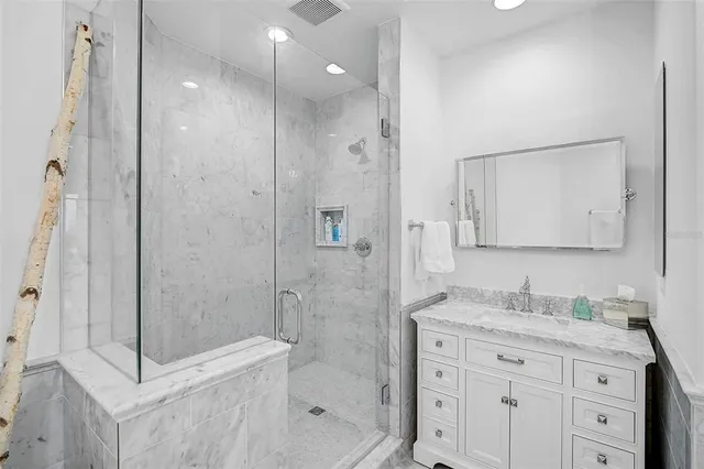 a bathroom with a granite countertop sink a mirror a shower and a mirror