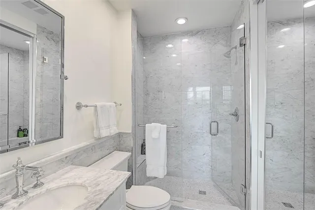 a bathroom with a granite countertop sink toilet and shower