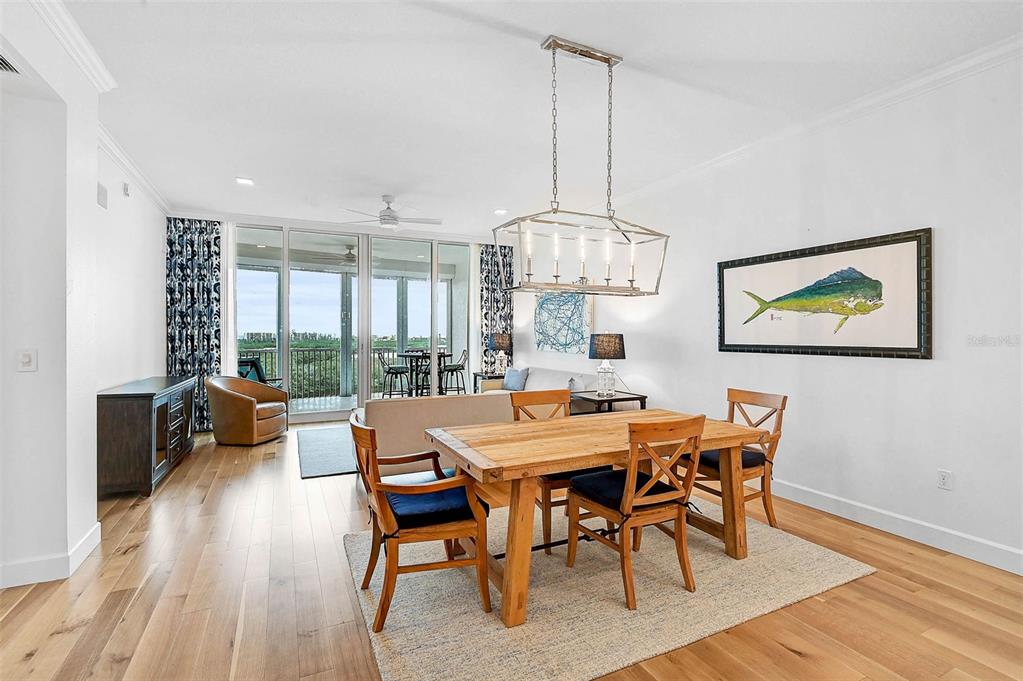 409 North Point Road, Unit 802 Osprey, FL 34229 - Photo 8 of 38 a view of a dining room with furniture a chandelier and wooden floor