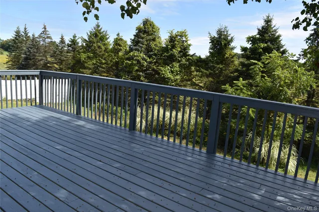 a balcony with wooden floor and trees in the back